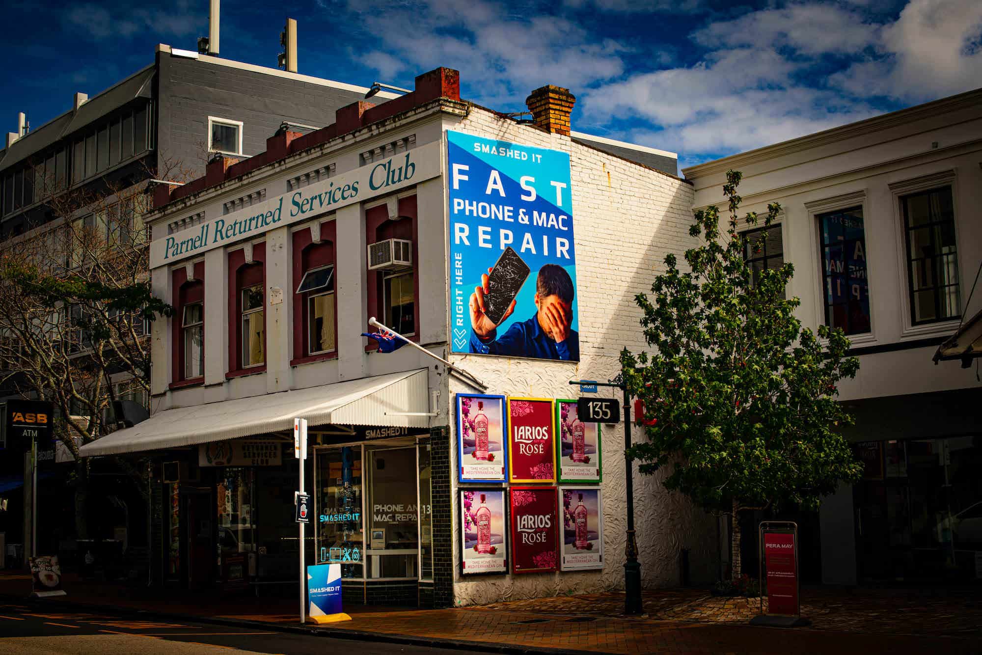 Exterior of the Parnell Store Smashed It with a large blue billboard promoting fast phone and Mac repair services.