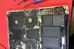 A disassembled MacBook Pro showing the internal motherboard, cooling fans, and battery during a repair process in Auckland.