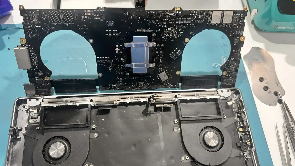 Case Study: MacBook Pro A2442 Liquid Damage Repair: From Dead to Perfect 4 MacBook Pro logic board lifted from chassis, showing power ICs and internal components likely damaged by incorrect charger specifications.